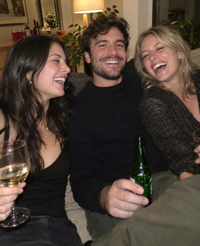 Phone photo of three friends laughing together on a sofa at a party